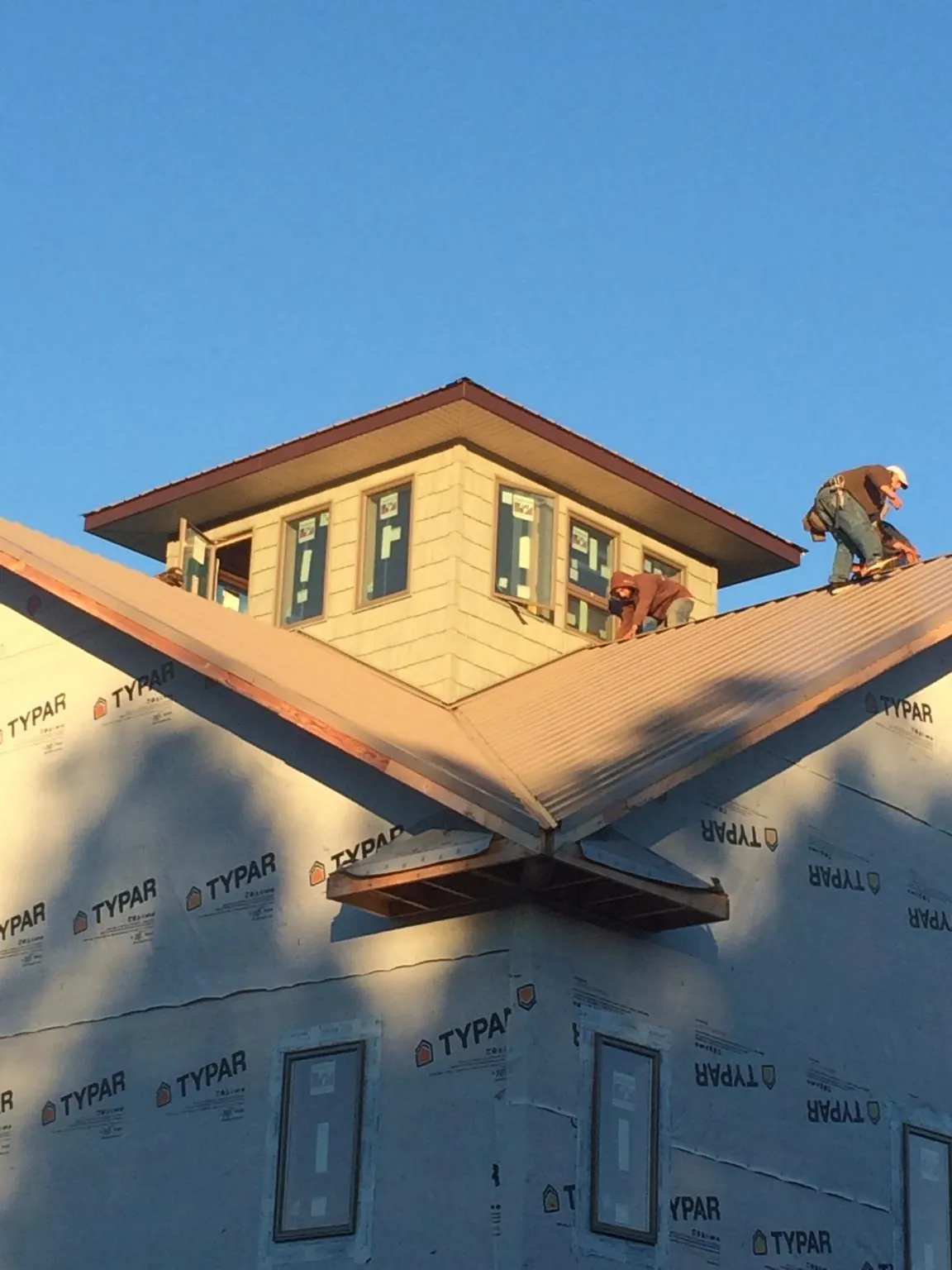 Roofers working around a rooftop cupola on a new metal roof at sunset — Roof Waterproofing in Irwin by Roofing Brothers
